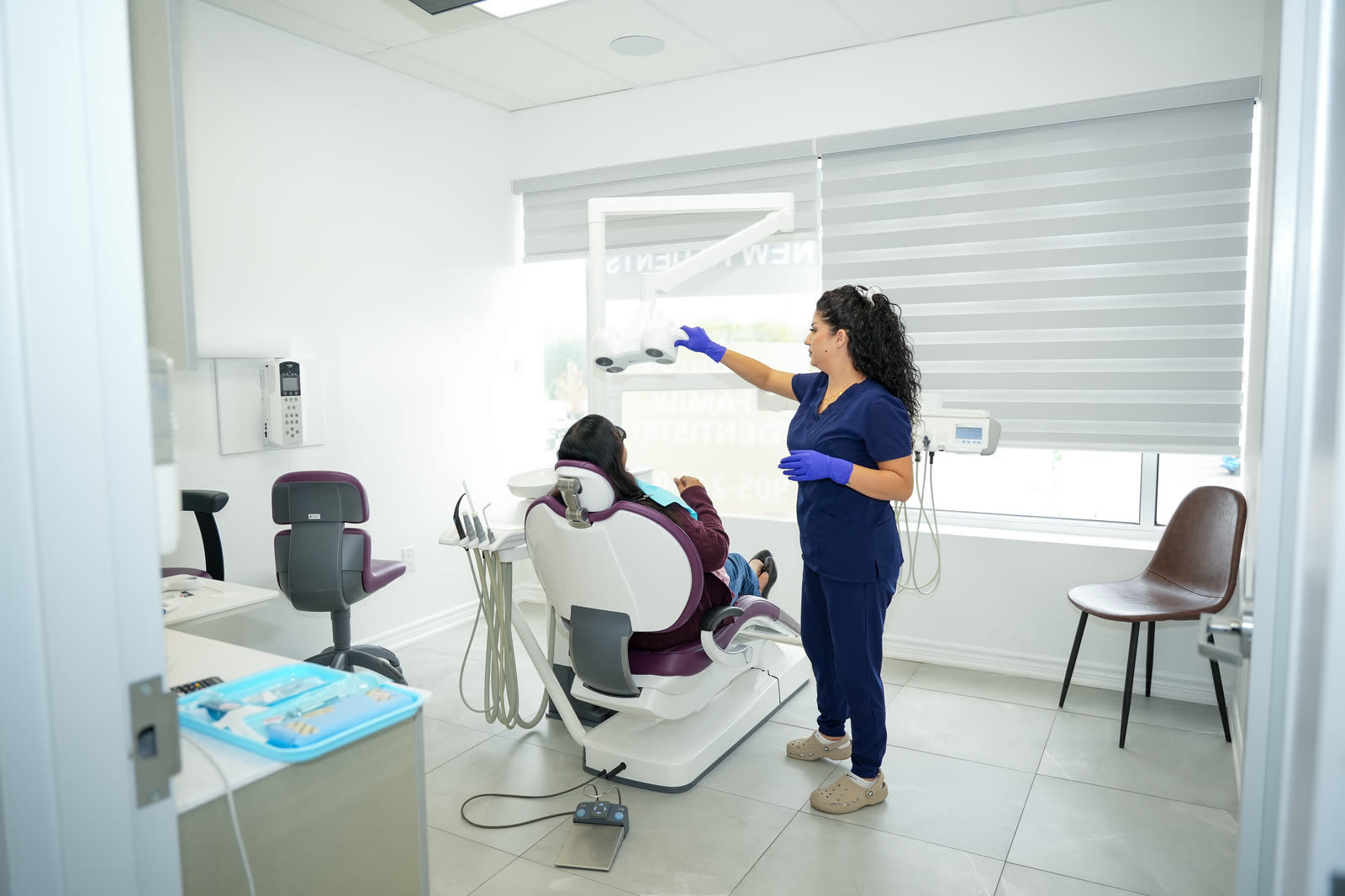 Shakila adjusting the dental light over a patient in a bright treatment room