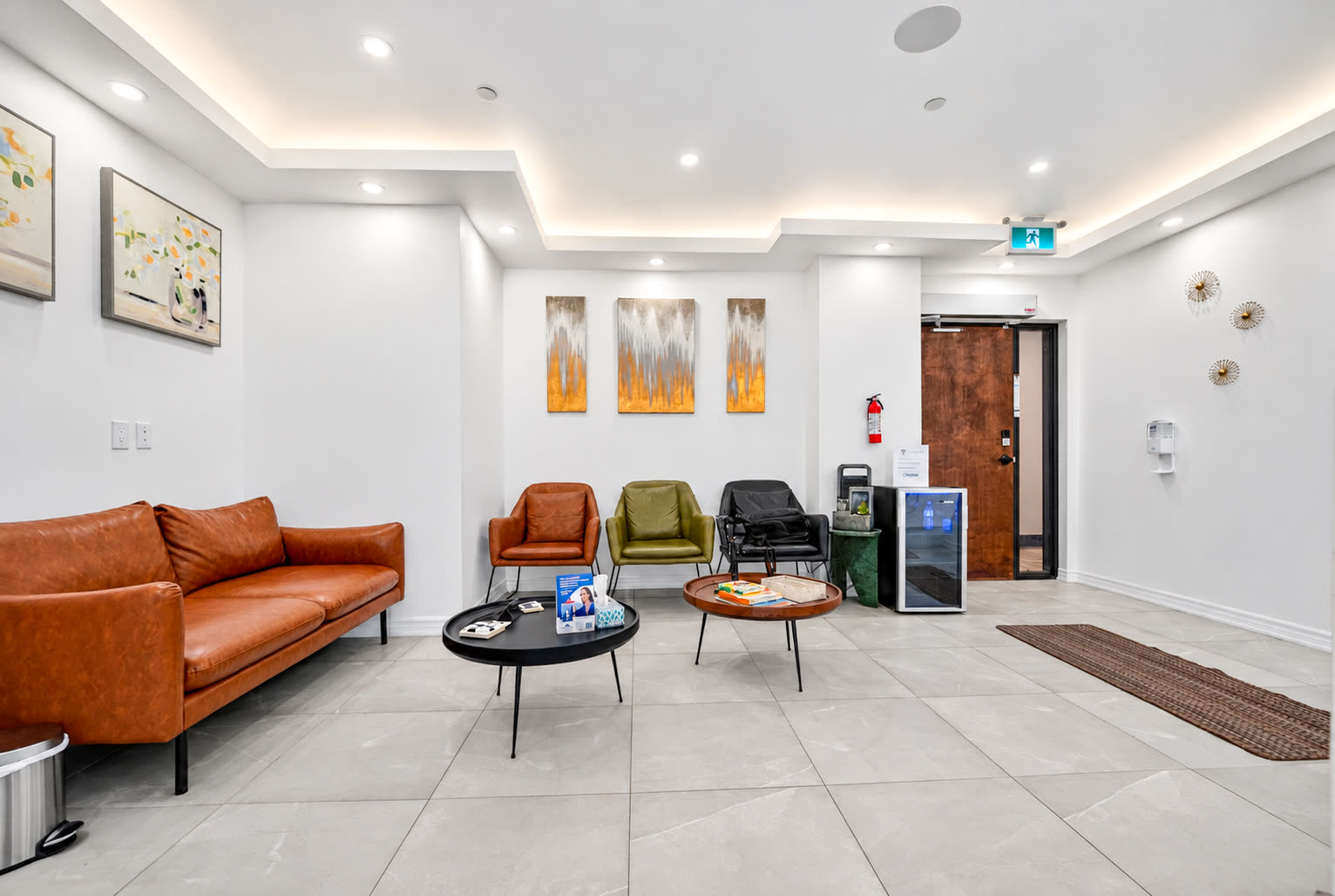 Waiting room with a leather sofa, armchairs and round coffee tables