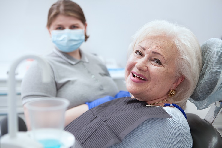 Smiling patient in a dental chair with a dental assistant